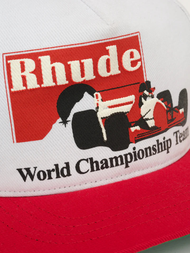 Close-up of Rhude Trophy Racing Hat showing Rhude logo, race car graphic, and World Championship Team text on white and red cap