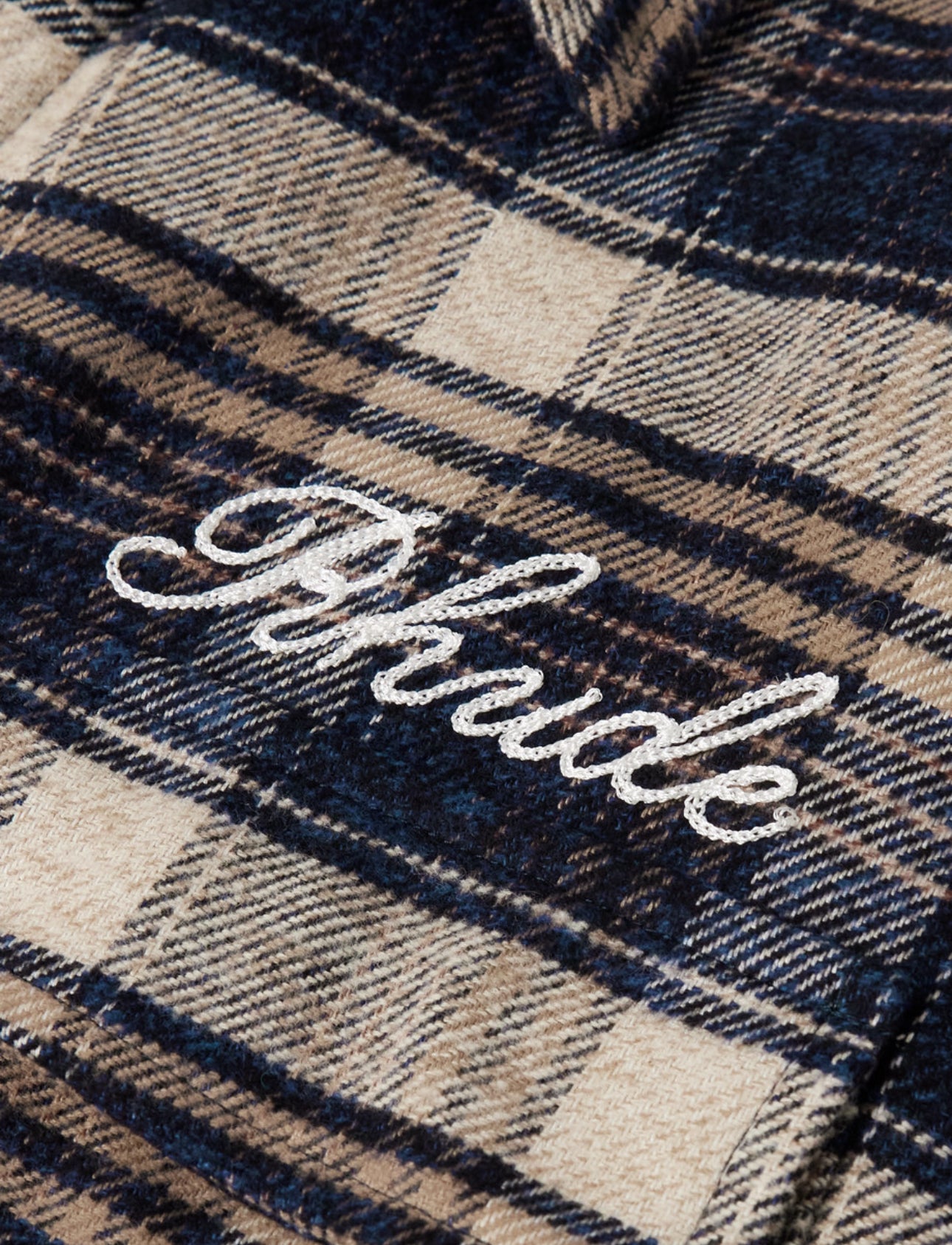 Close-up of Rhude Script Logo Flannel showing embroidered Rhude logo on plaid wool fabric
