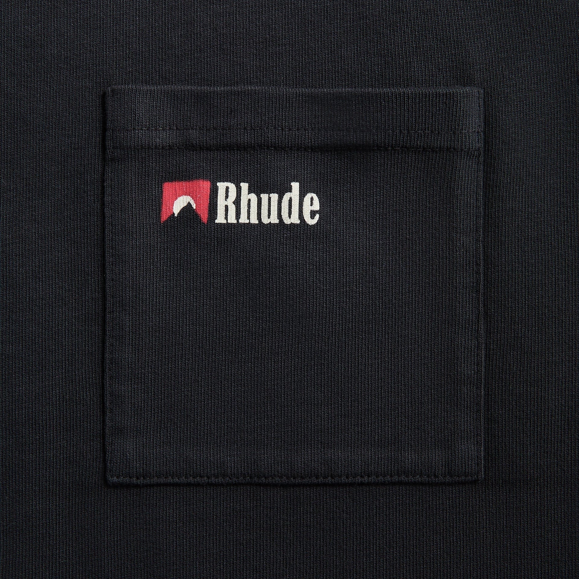 Close-up view of Rhude Moonlight Wolf Pocket Tee pocket with Rhude logo embroidery on black vintage wash cotton fabric
